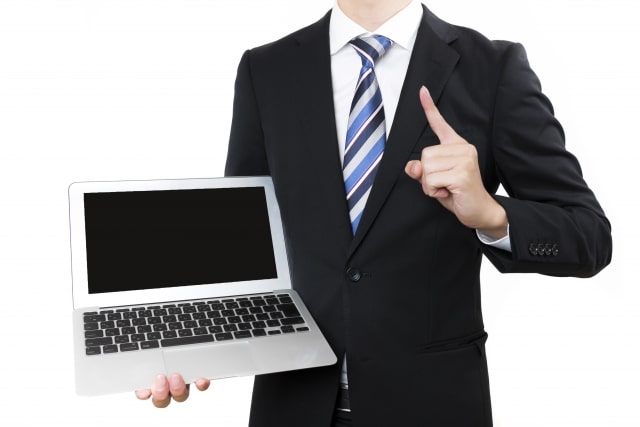 PCをこちらに向けて立つ人物